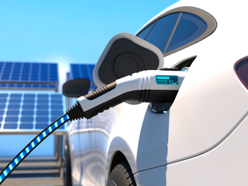 Electric car charging with solar panels in background