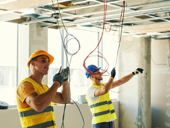 Two electricians working on a tenant buildout project